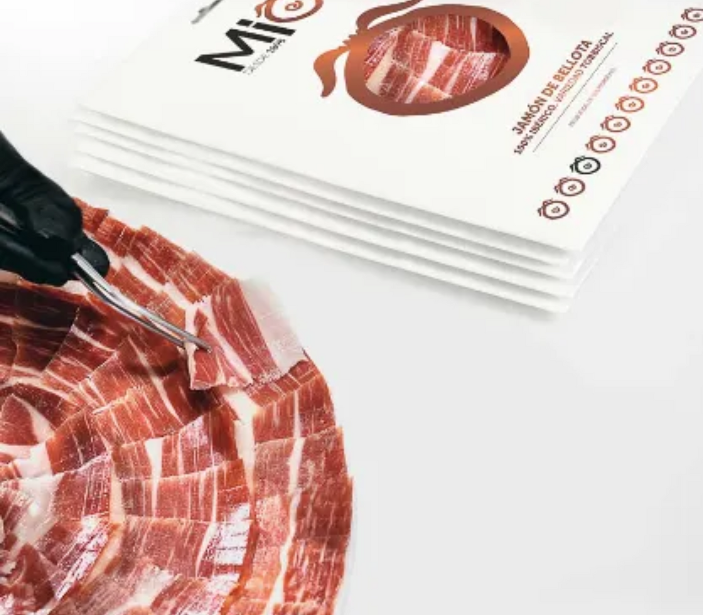 Se muestra un plato de jamón ibérico y varios sobres de jamón blancos.