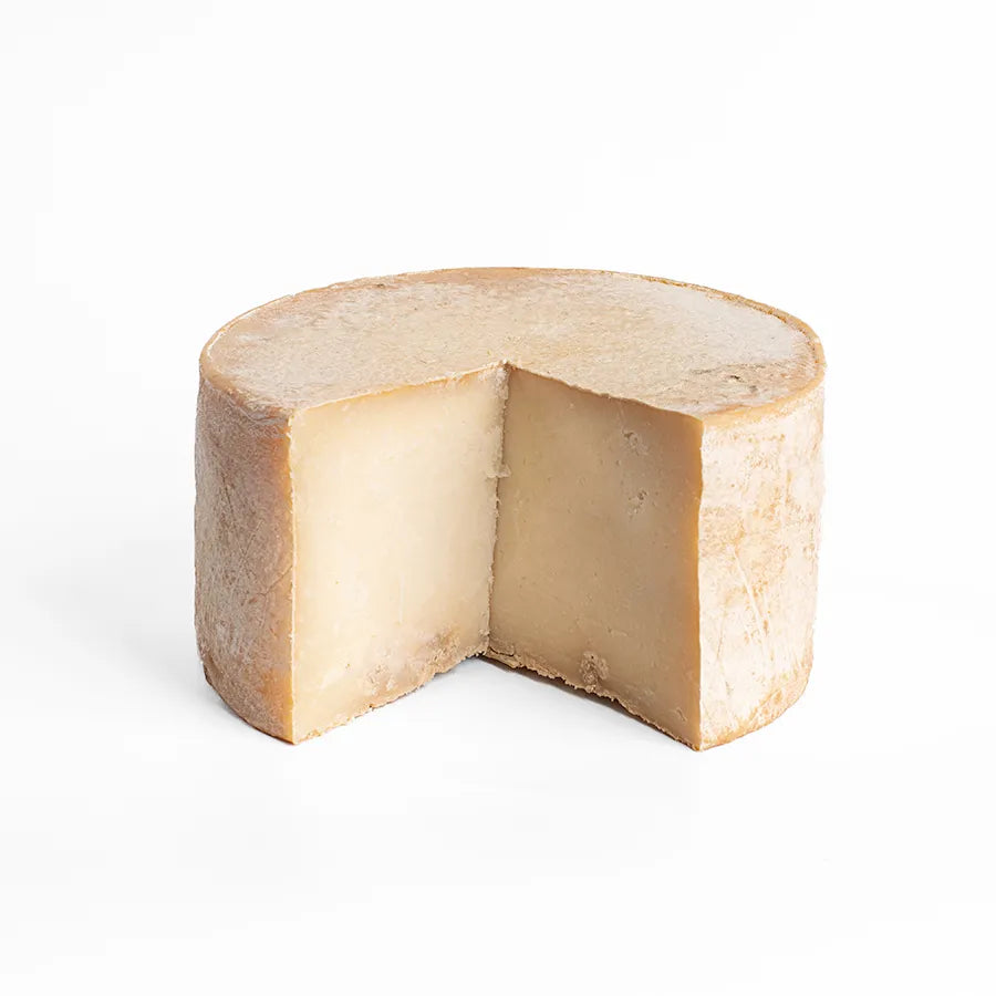 Se muestra un queso con una cuña cortada donde se aprecia su textura interior.