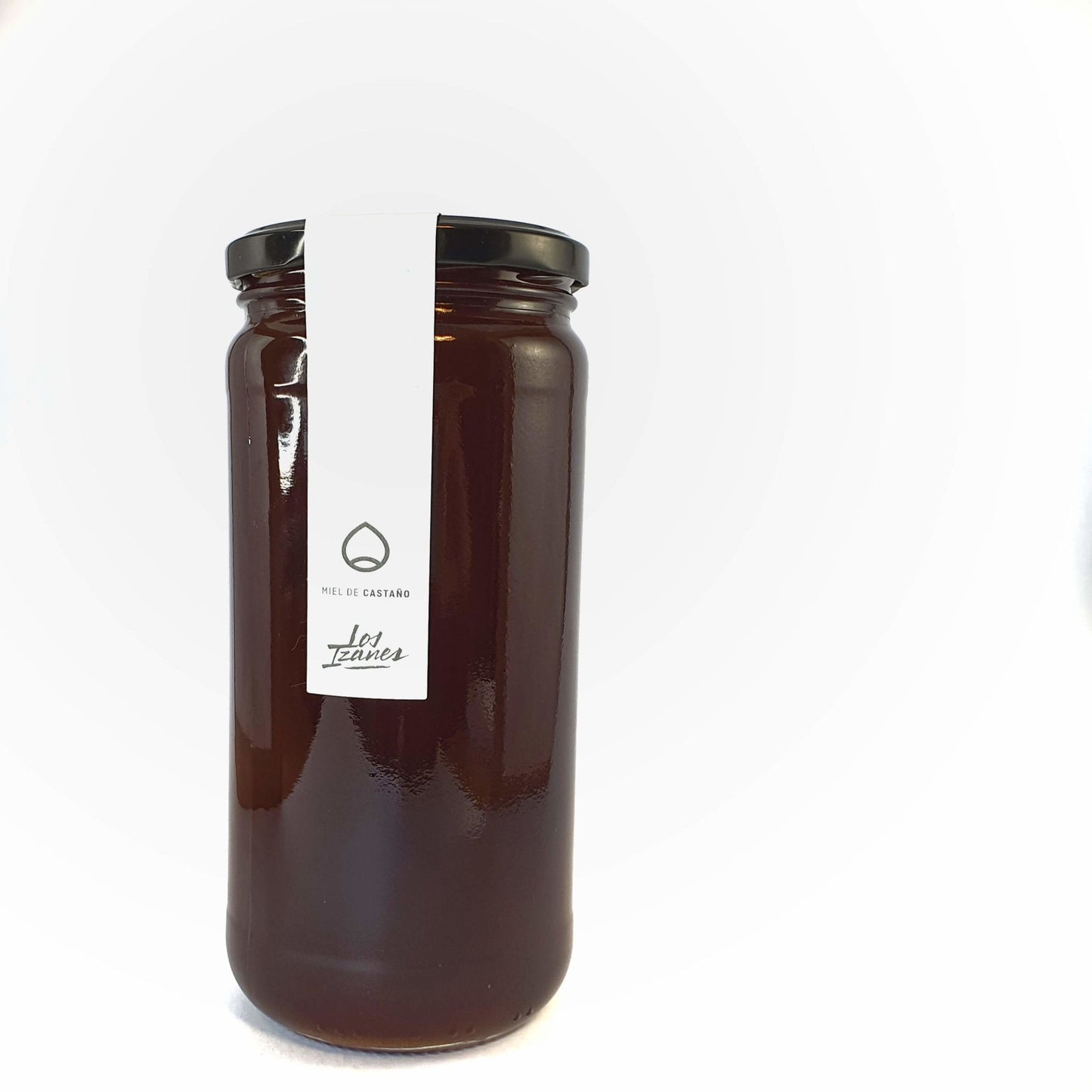 Se muestra un tarro de miel de castaño muy oscura sobre un fondo blanco.