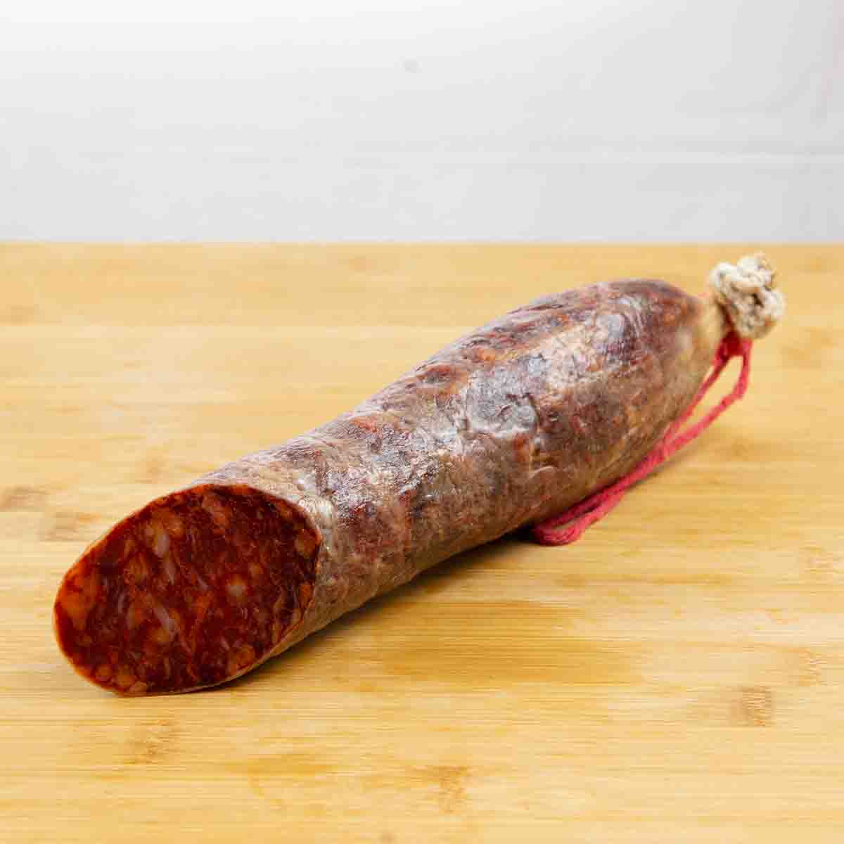 Muestra la mitad de un chorizo cular cortado. En el corte se puede ver la grasa y carne del chorizo.