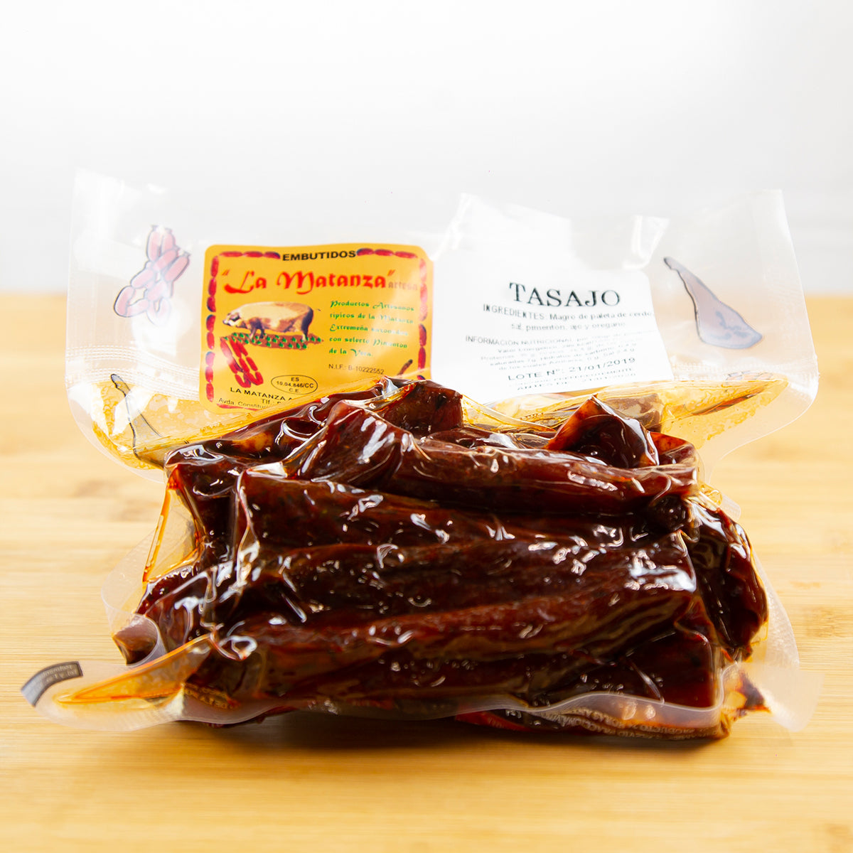 Paquete de tasajo de cerdo envasado al vacío sobre una tabla marrón.