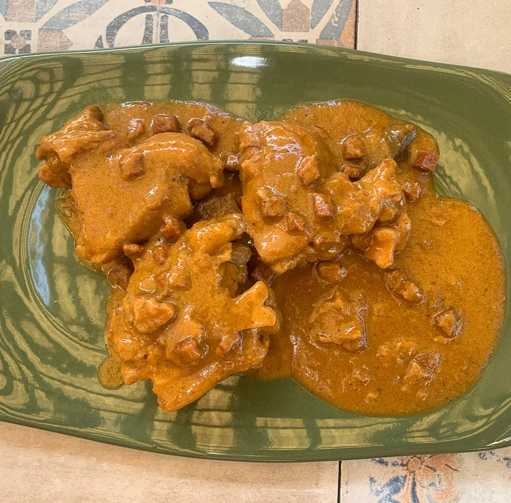 Se muestra un plato verde con unas manitas de cerdo y un salsa de color naranja.