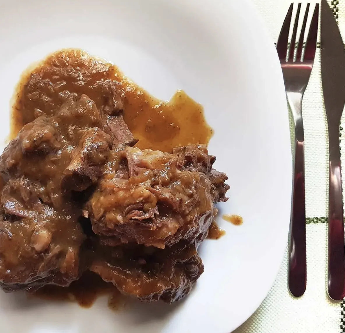 Se muestra una ración de rabo de toro sobre un plato blanco.