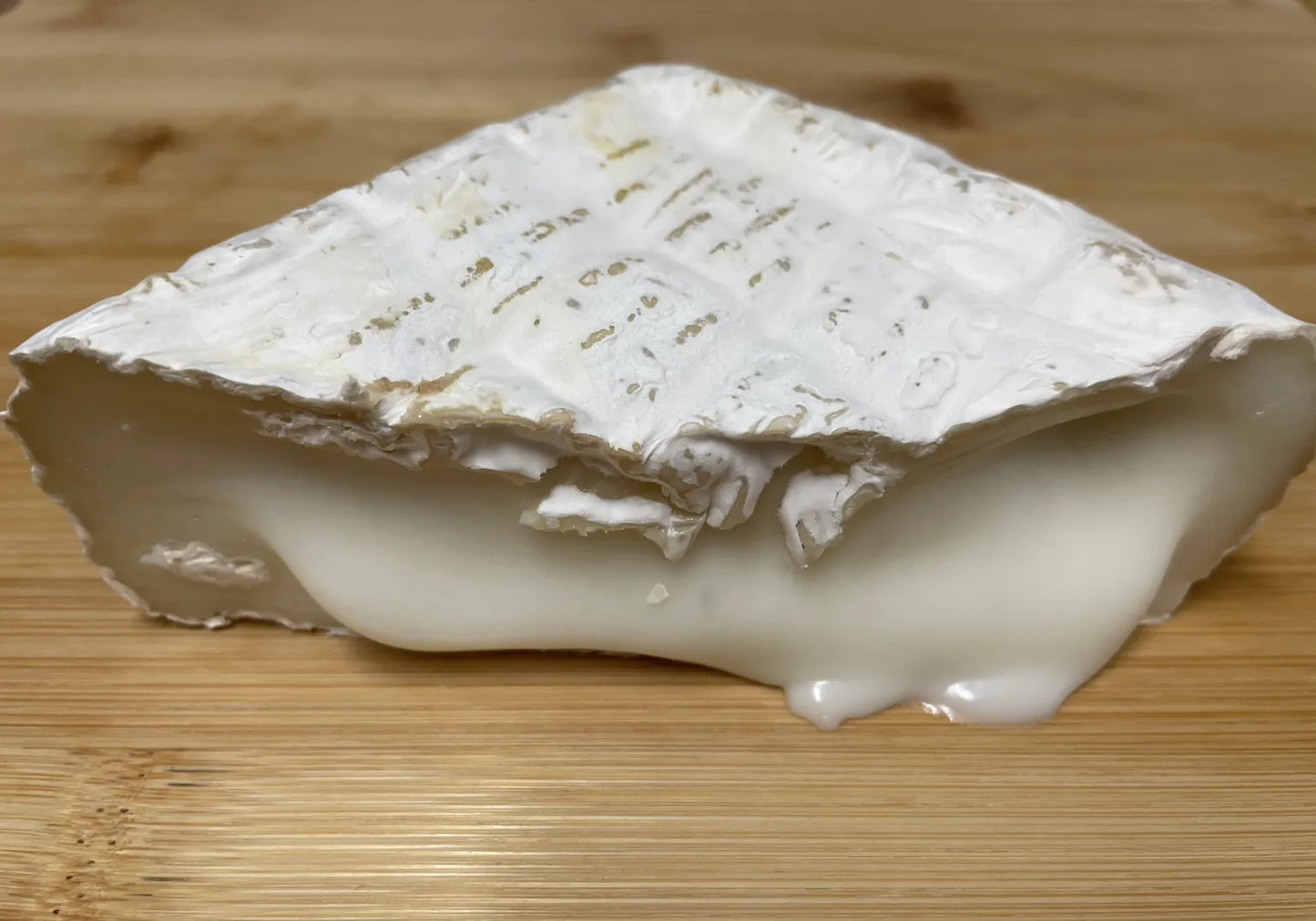 Cuña de queso en la que se muestra el queso con gran cremosidad, casi derritiéndose.