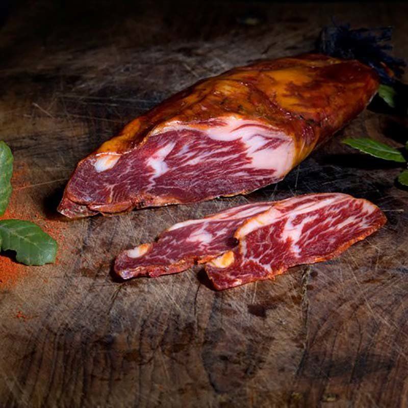 Se muestra una pieza de lomito cortada con dos rodajas sobre una tabla de madera. Se aprecia el extraordinario veteado de la grasa.