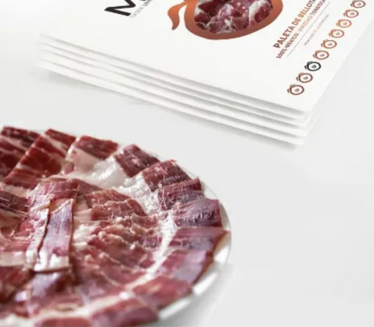 Se muestra un plato de paleta ibérica y varios sobres de paleta de color blanco.