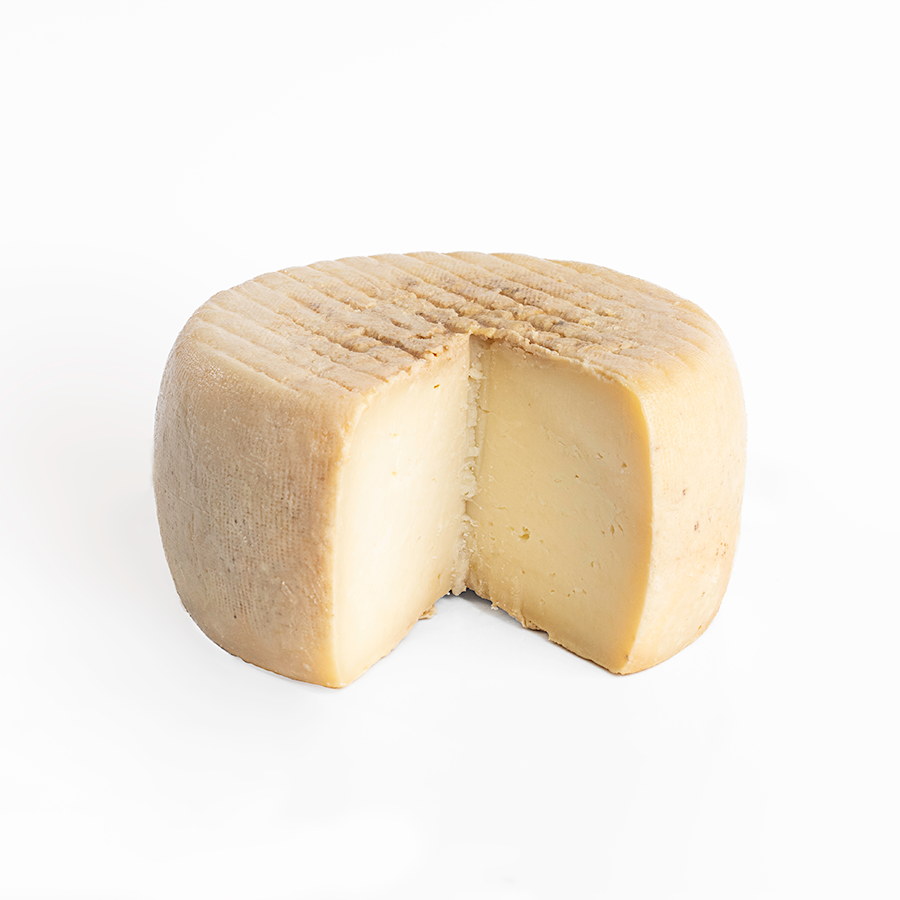 Se muestra un queso entero con una cuña cortada donde se aprecia su interior. De corteza ligeramente amarillenta y interior compacto. Muy apetecible.