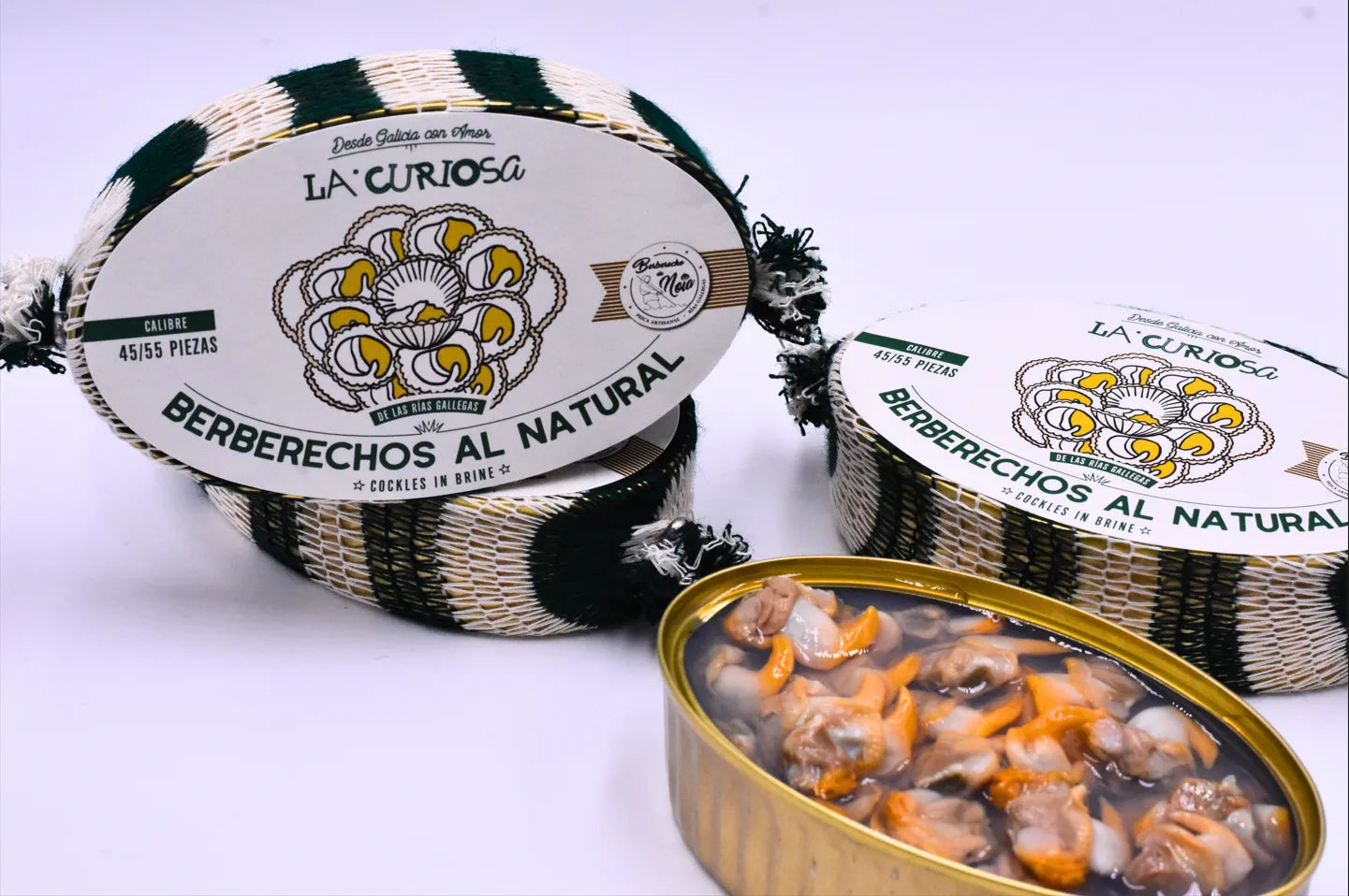 Se muestra 4 latas de berberechos y una de ellas abierta con los berberechos. El fondo es blanco.