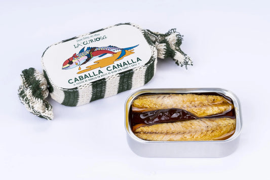 Se muestran dos latas de caballa, una de ellas sin tapa en la que se aprecia la caballa y una guindilla.
