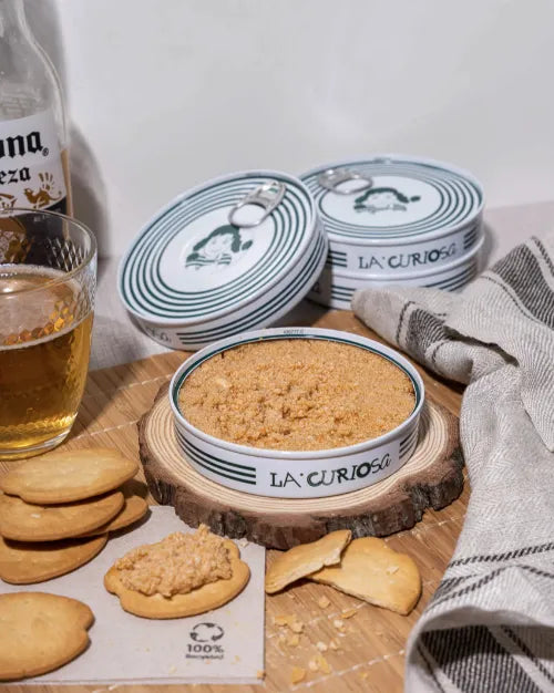 Se muestran varias latas de huevas picantes, y una de ellas está abierta y con un canapé untado. 