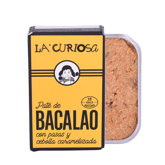 Se muestra una lata de paté de bacalao con su caja amarilla. Se aprecia la textura untuosa del paté.