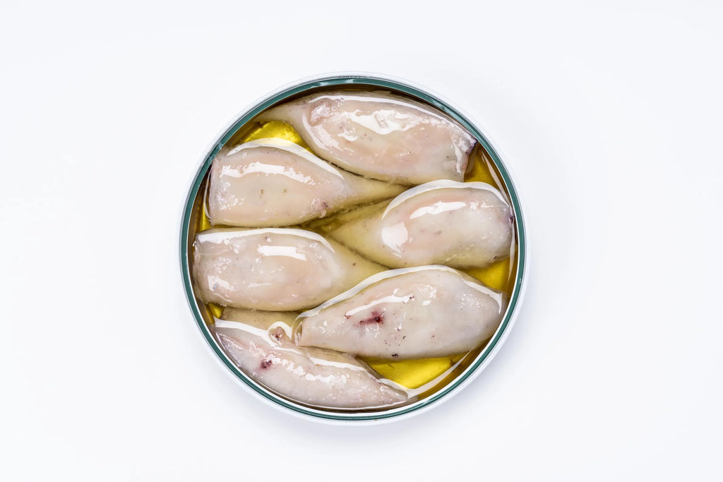 Se muestra una lata de chipirones sin tapa donde se ven los chipirones en salsa.