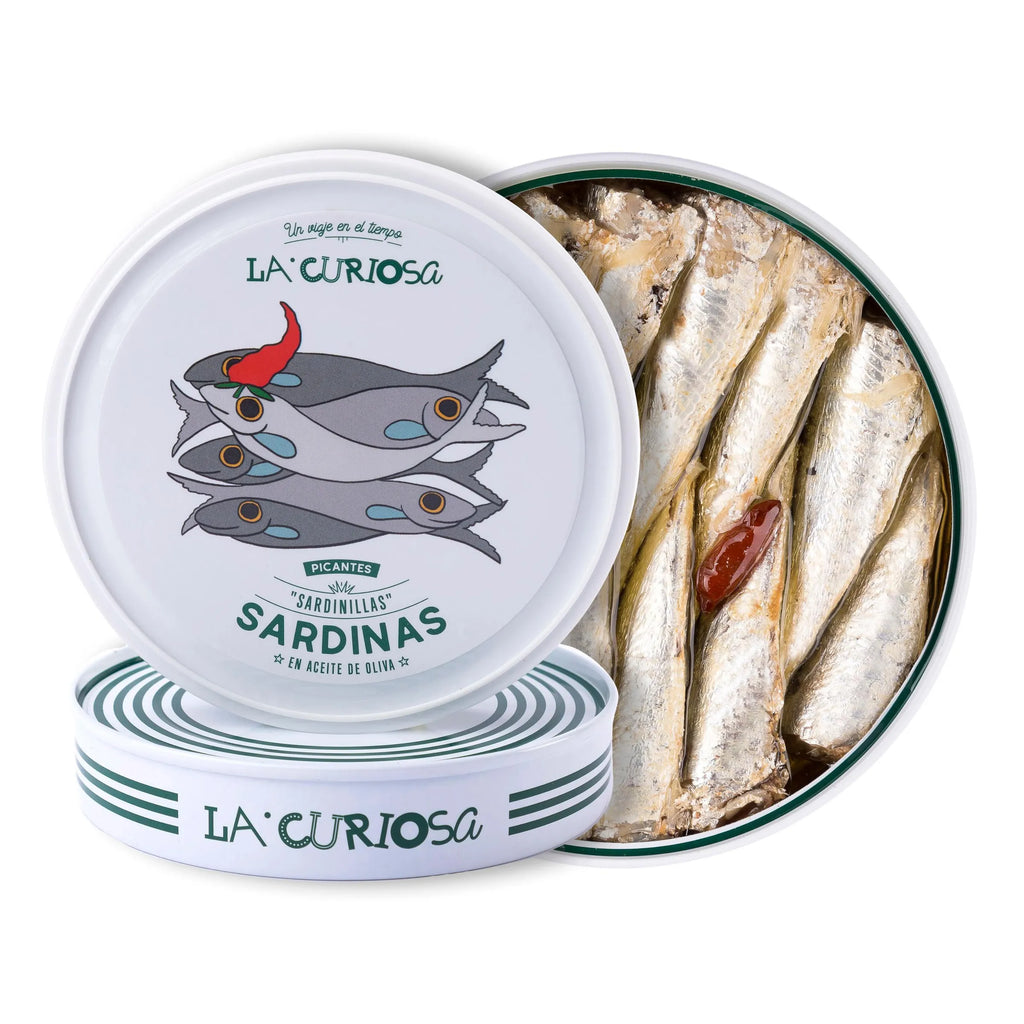 Se muestran dos latas de sardinillas y una de ellas sin tapa, donde se aprecian las sardinillas y una guindilla.