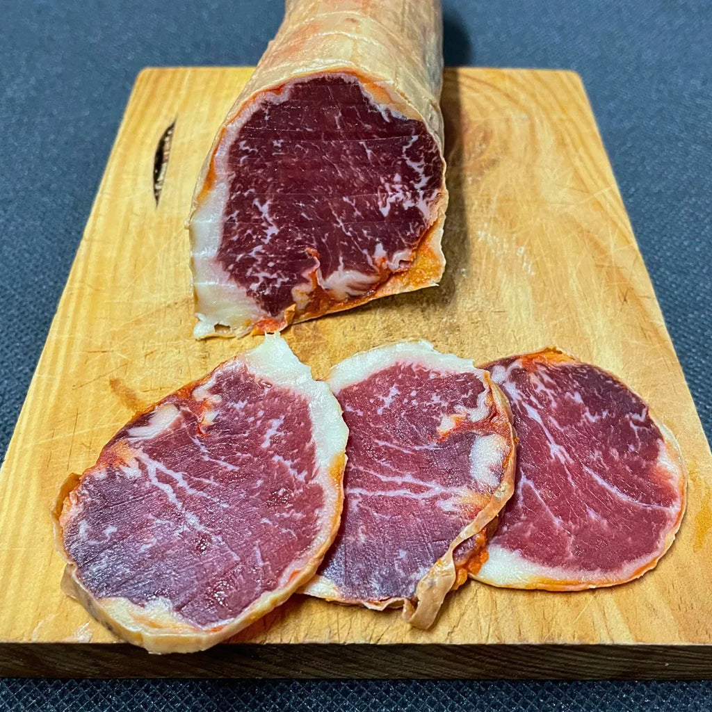 Se muestra un lomo ibérico cortado sobre una tabla de madera.