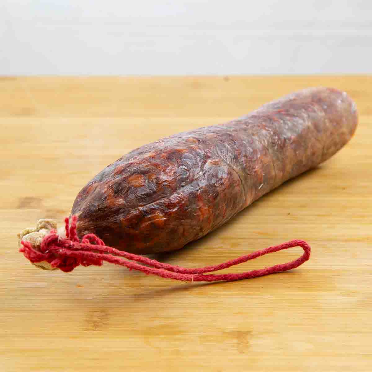 Chorizo cular entero puesto una tabla marrón claro.