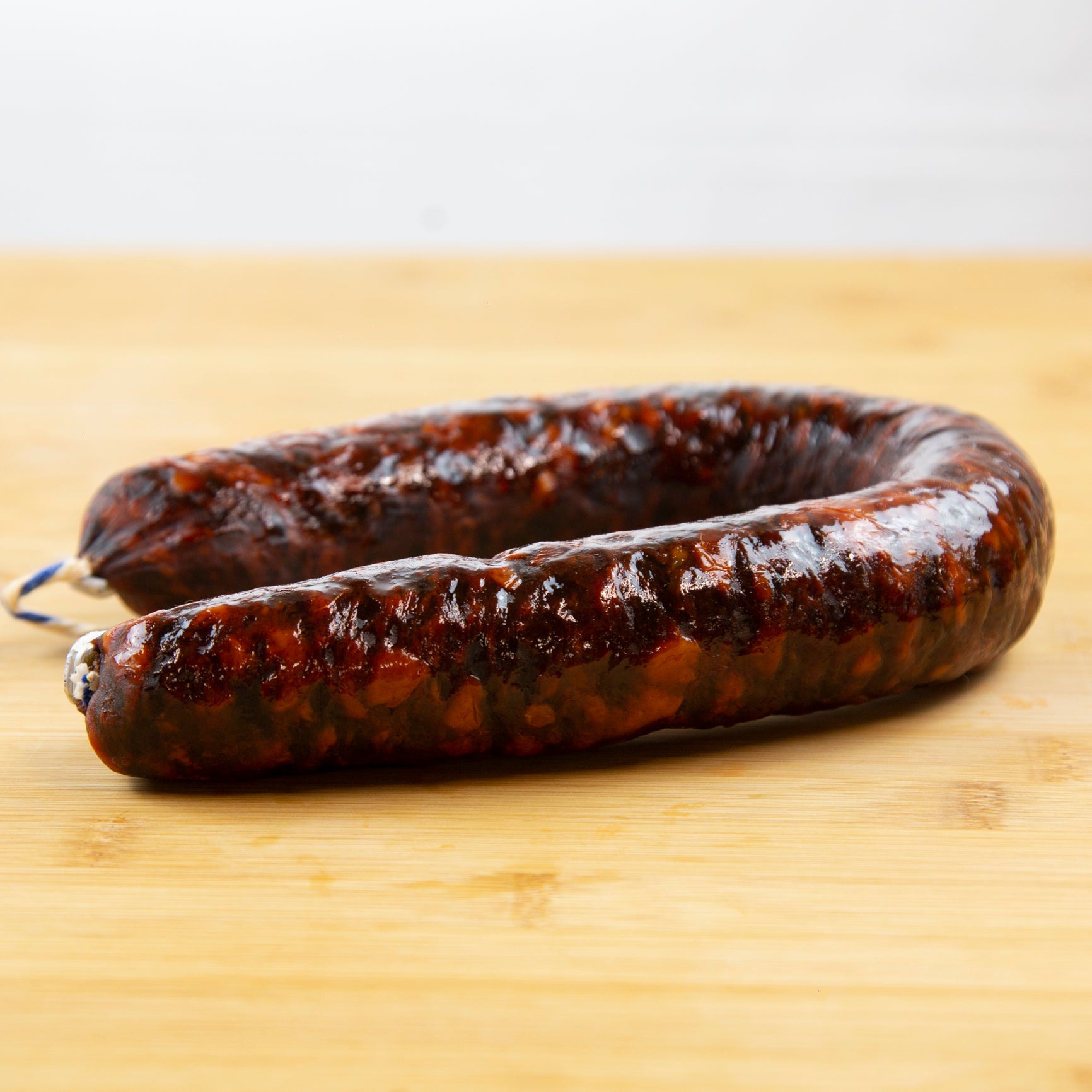Muestra un chorizo de herradura sobre una tabla de madera de color marrón claro.