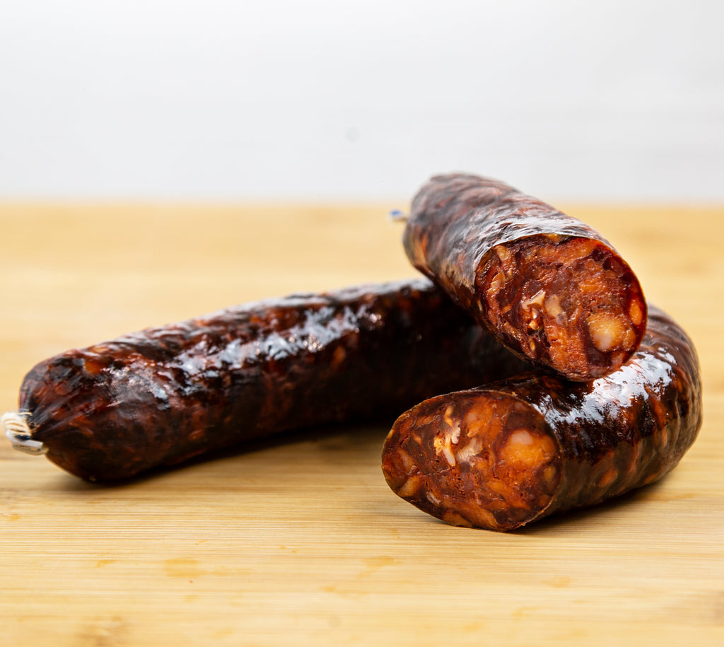 Muestra un chorizo de herradura cortado a la mitad sobre una tabla de madera de color marrón claro.