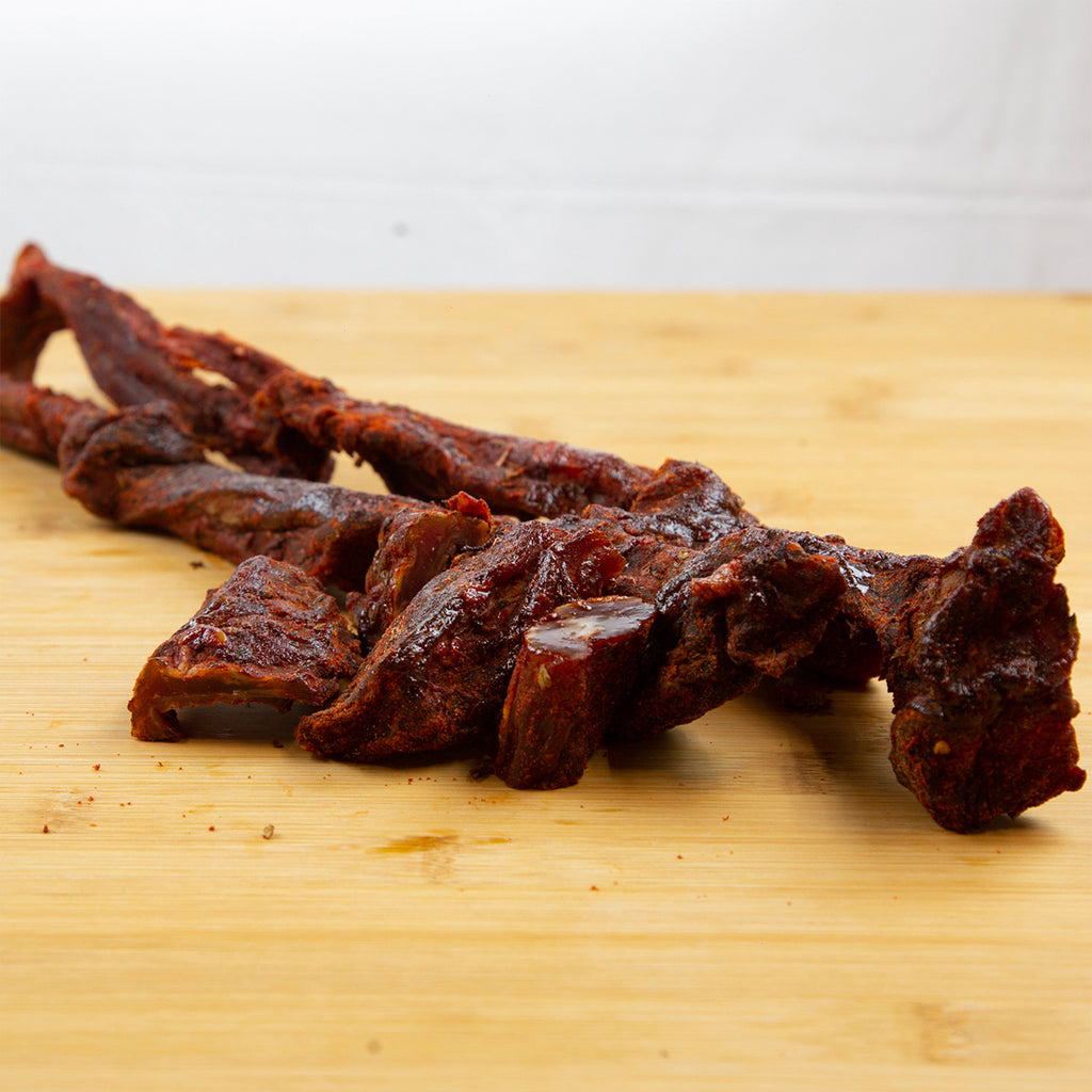 Tasajo en el que se aprecia la carne sazonada con pimentón sobre tabla marrón