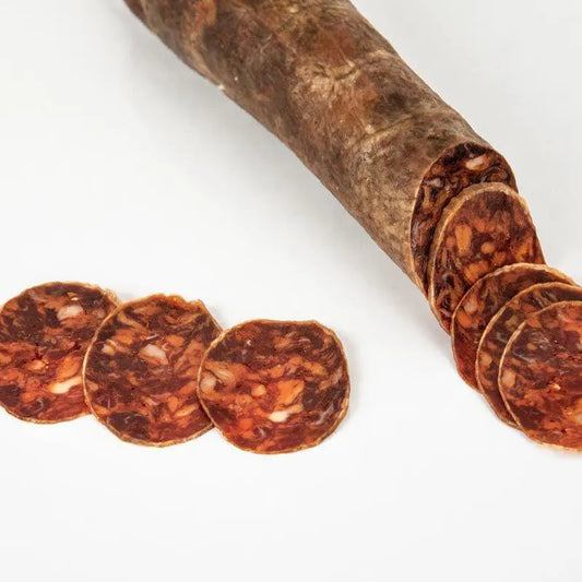 Chorizo artesanal con varias rondas cortadas sobre un fondo blanco.