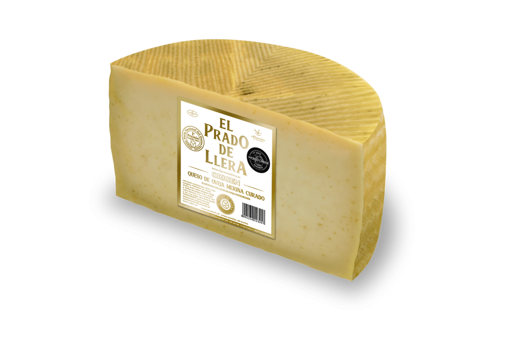 Se muestra medio queso Prado de Llera Origen partido por la mitad, con su etiqueta en el costado.