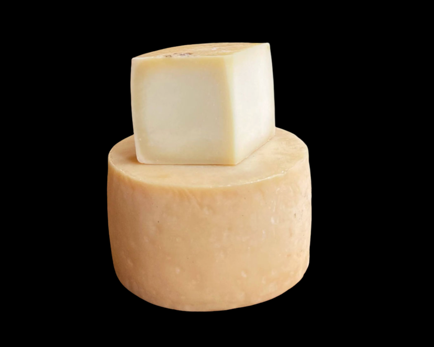 Se muestra un queso dop idiazabal natural con una cuña sobre ese mismo queso. El fondo es negro.