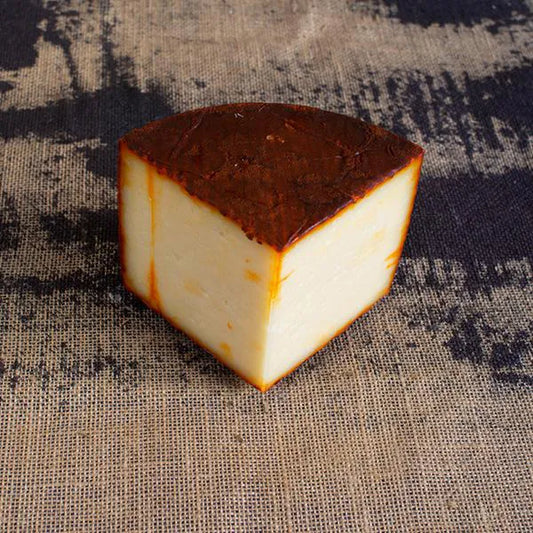 Cuña de queso con corteza roja del pimentón.