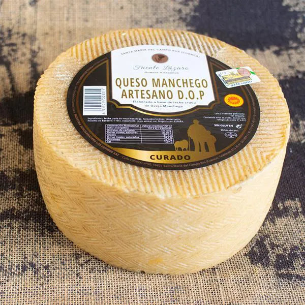 Se muestra un queso entero de corteza amarillenta con una etiqueta negra en su base superior.