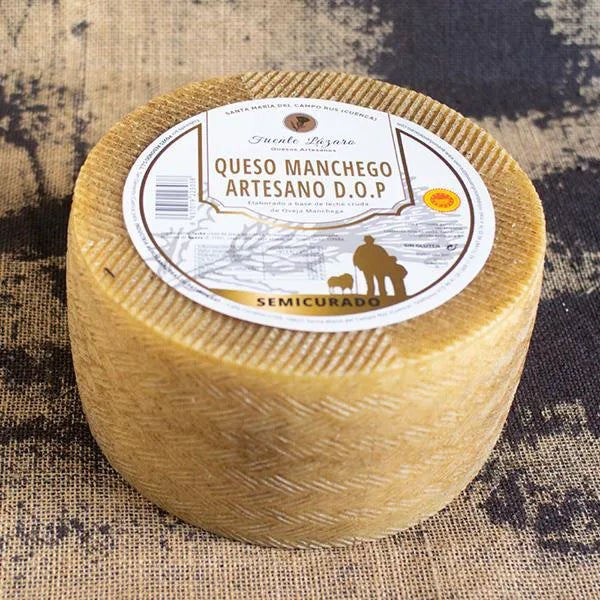 Se muestra un queso entero de corteza amarillenta con una pegatina blanca en su base superior.