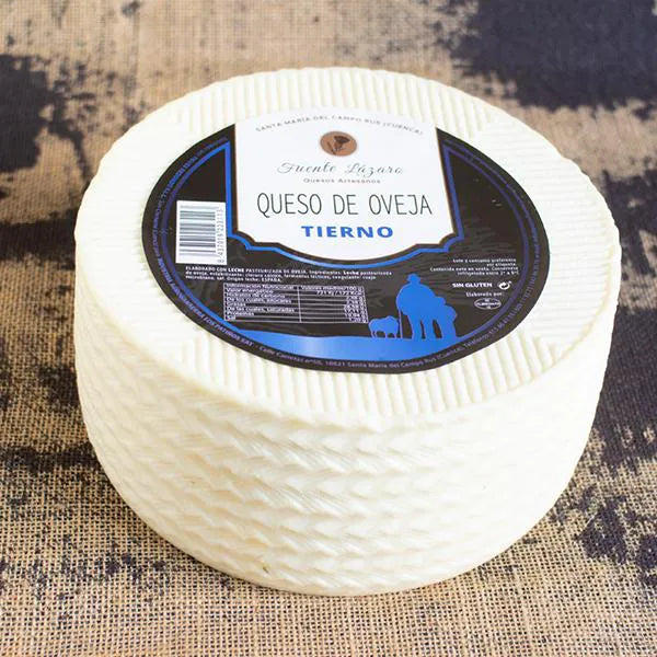 Queso entero de corteza blanca con etiqueta del productor en su base superior.
