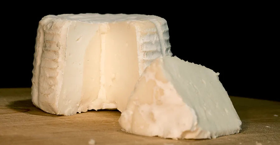Se muestra un queso muy blanco partido. Se aprecia su textura compacta.