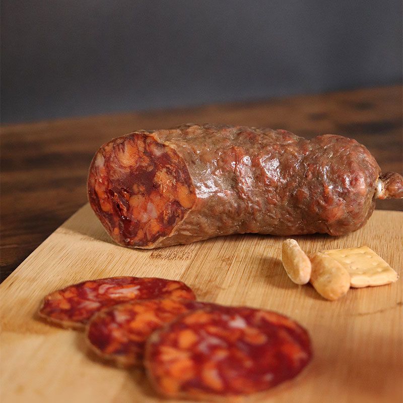 Chorizo ibérico cortado con varias rodajas sobre una tabla de madera.